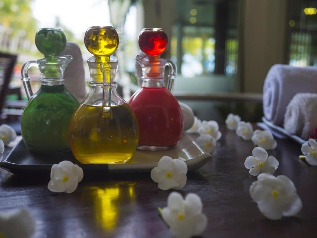 Frasco de aceite de masaje con flores y piedras decorativas al lado